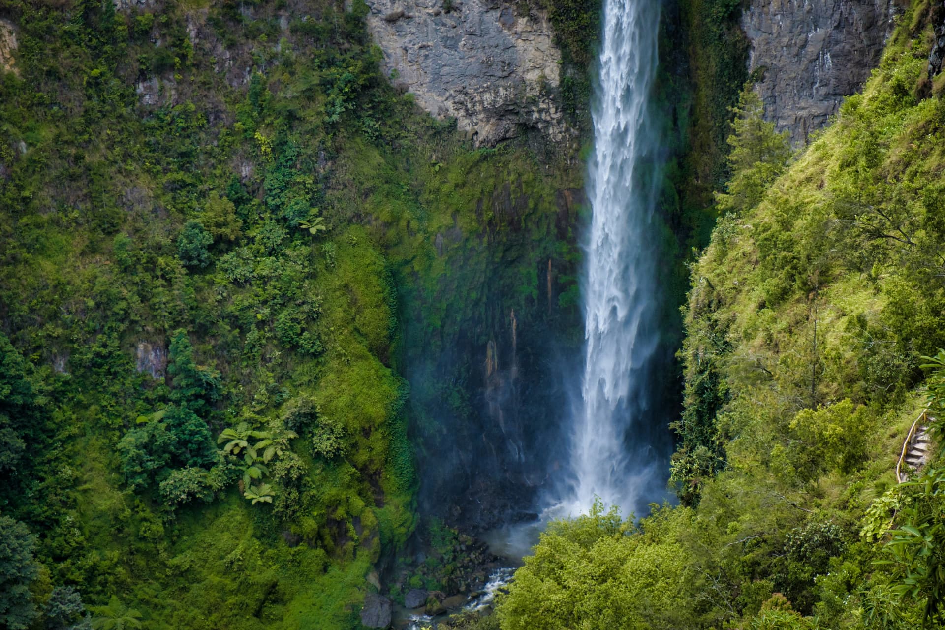 Tall waterfall surrounded by lush green rainforest in North Sumatra
