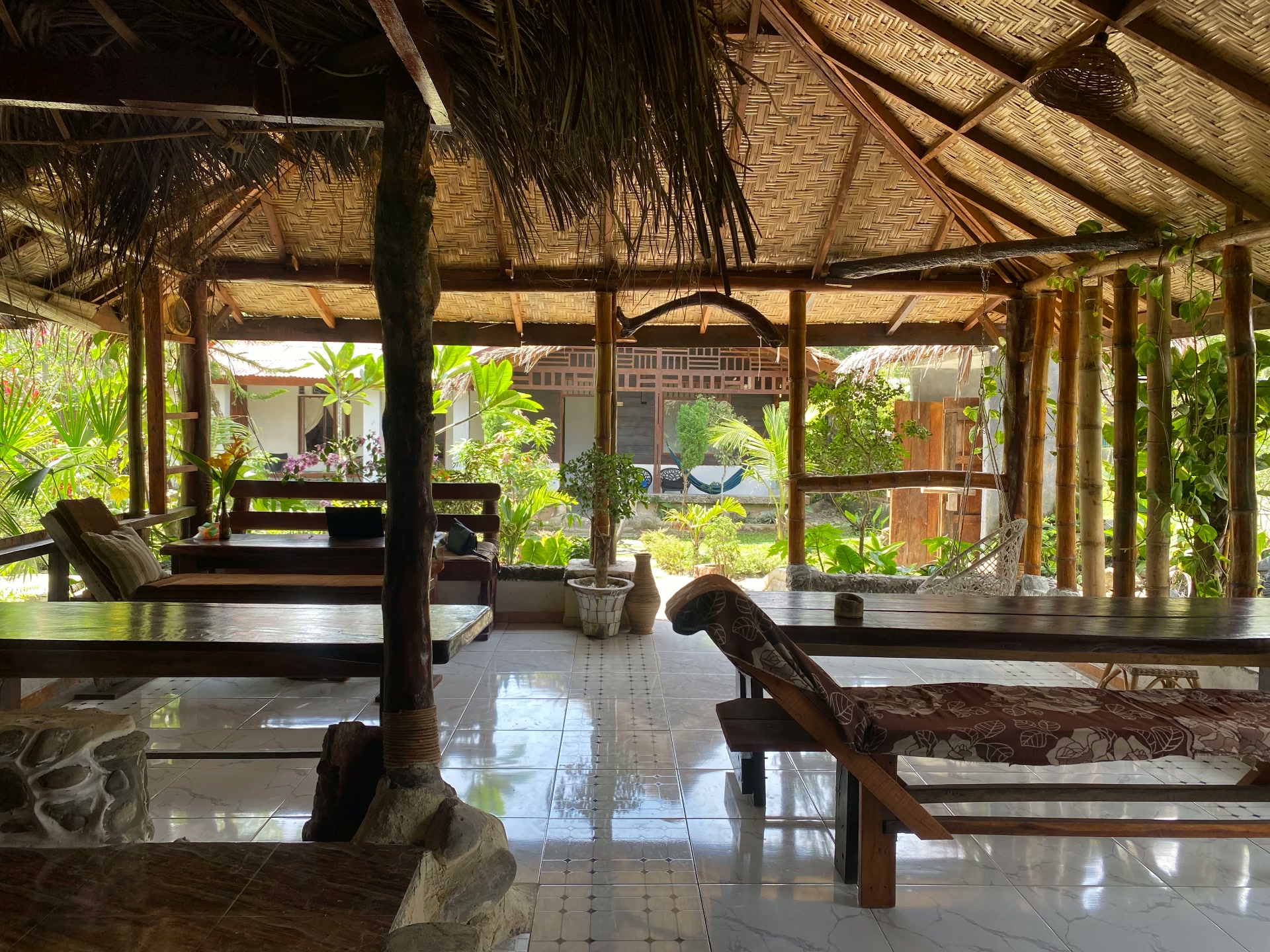 Open-air thatched restaurant with wooden tables and tropical garden at Villa Paradise guest house in Bukit Lawang, North Sumatra