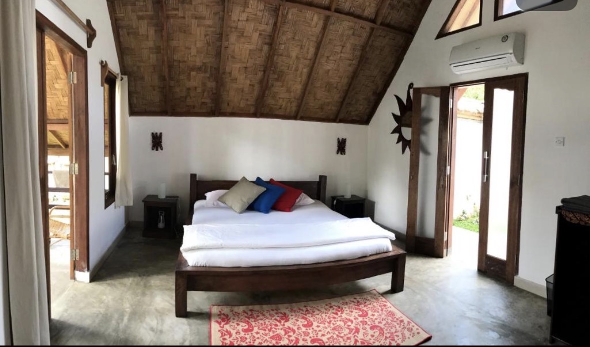 Air-conditioned bungalow room with queen-size bed and mosquito net at Villa Paradise guest house in Bukit Lawang, North Sumatra