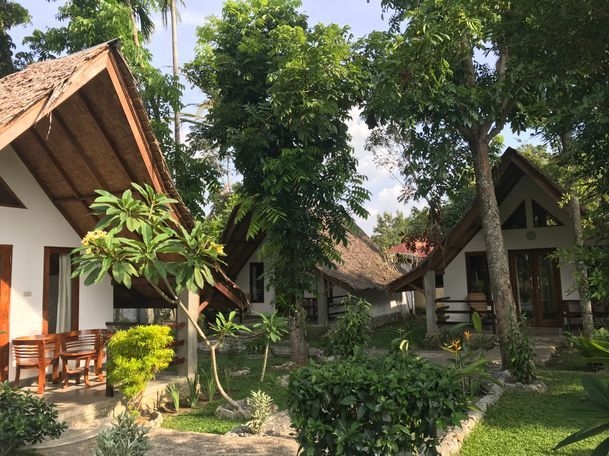 Thatched-roof bungalows surrounded by a tropical garden at Villa Paradise guest house in Bukit Lawang, North Sumatra