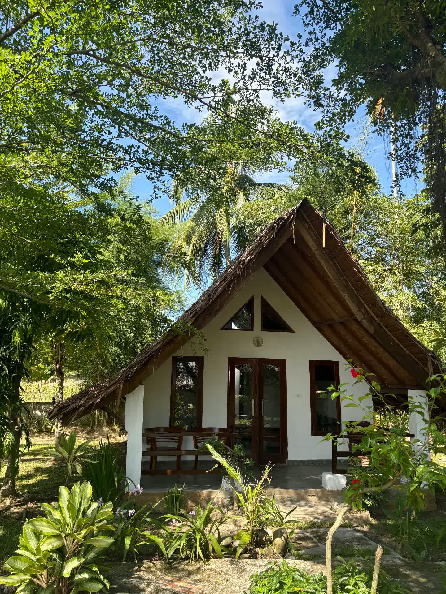 Thatched-roof bungalow surrounded by a tropical garden at Villa Paradise guest house in Bukit Lawang, North Sumatra